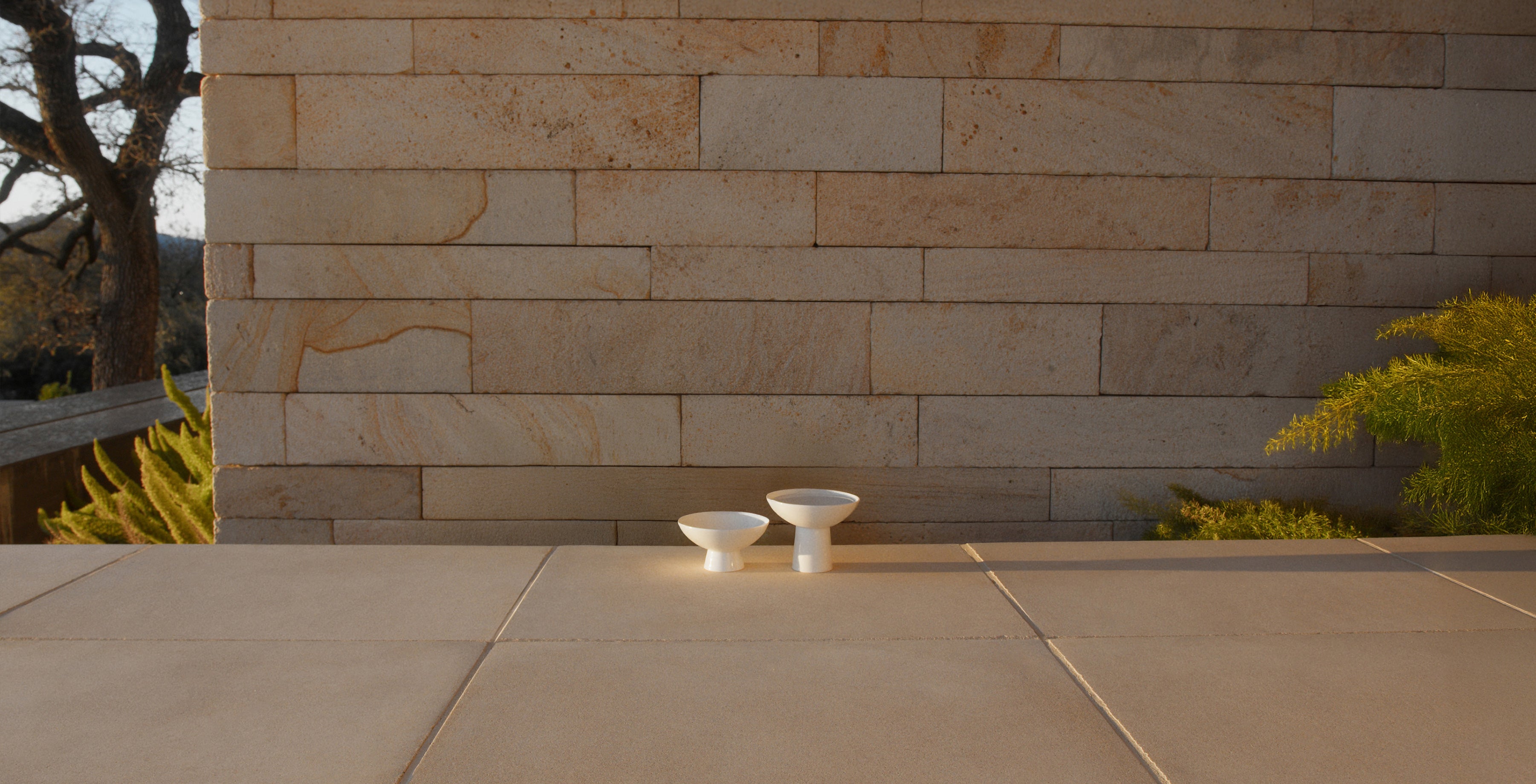 Duomo porcelain elevated bowls shown outdoors on stone terrace - centered
