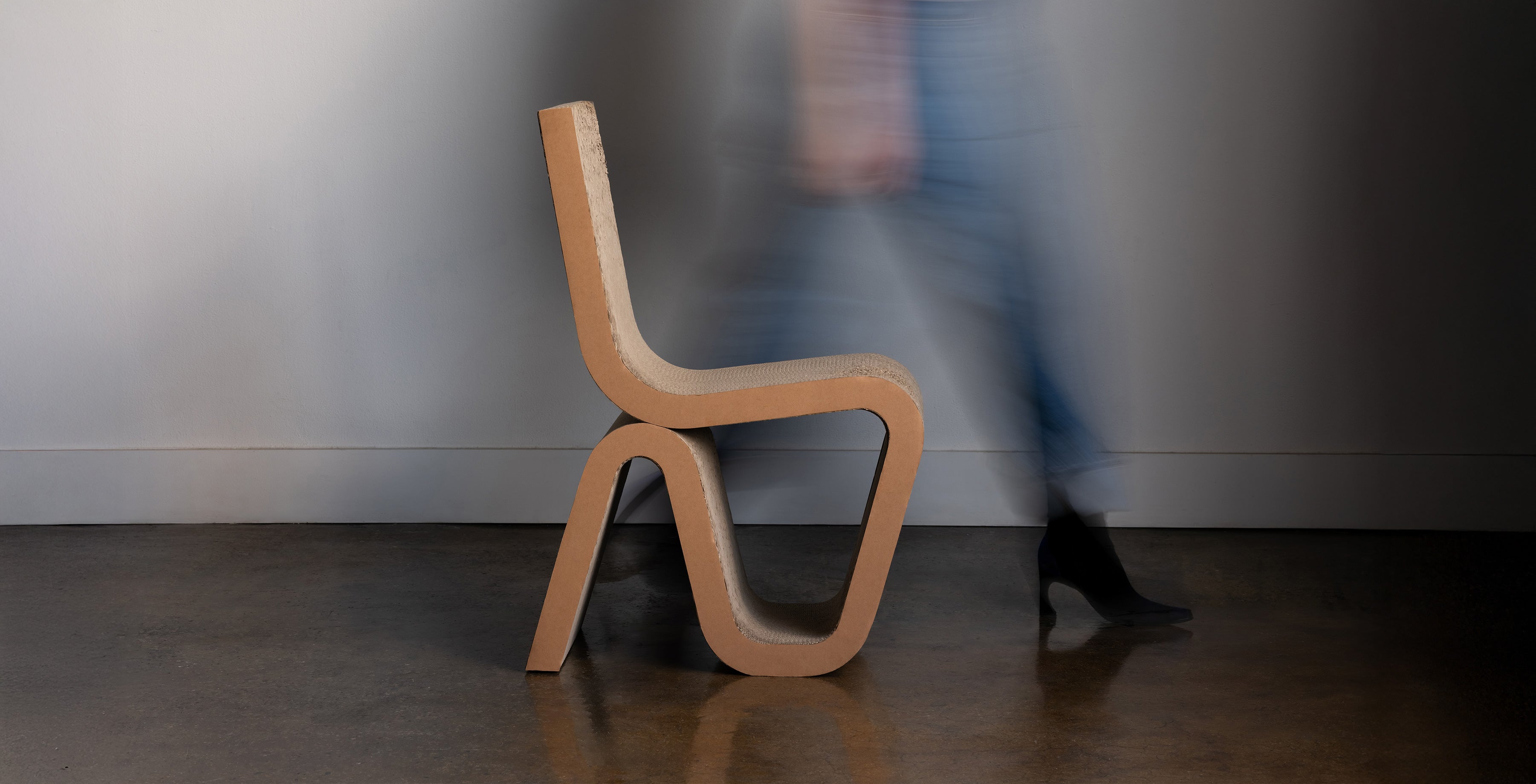 Rumi sculptural cat scratcher chair made of layered cardboard with person walking past