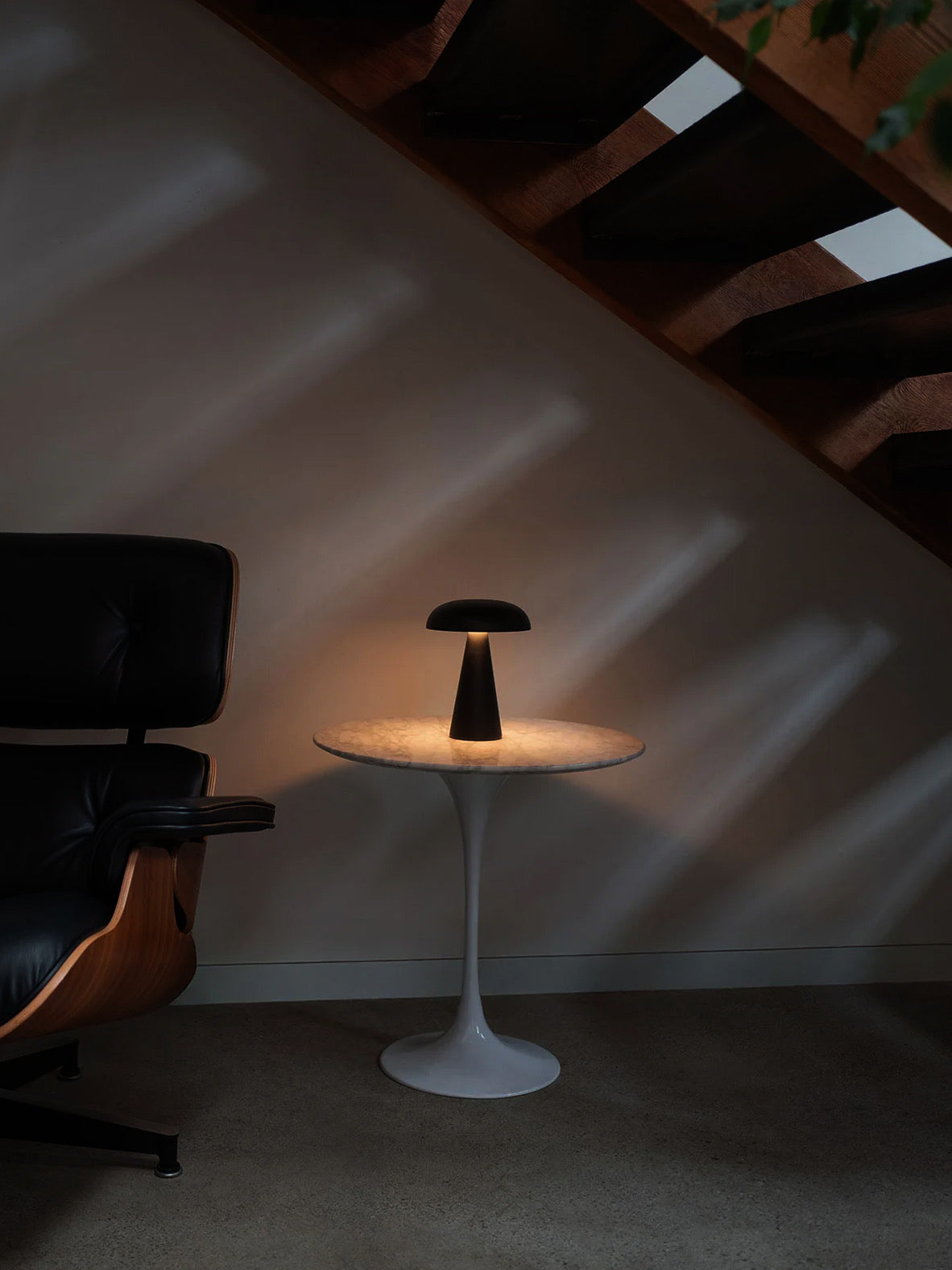 Reverie portable lamp positioned beside chair in modern interior